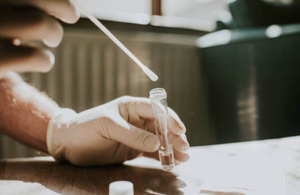 a man wearing a glove putting a test sample on a test tube